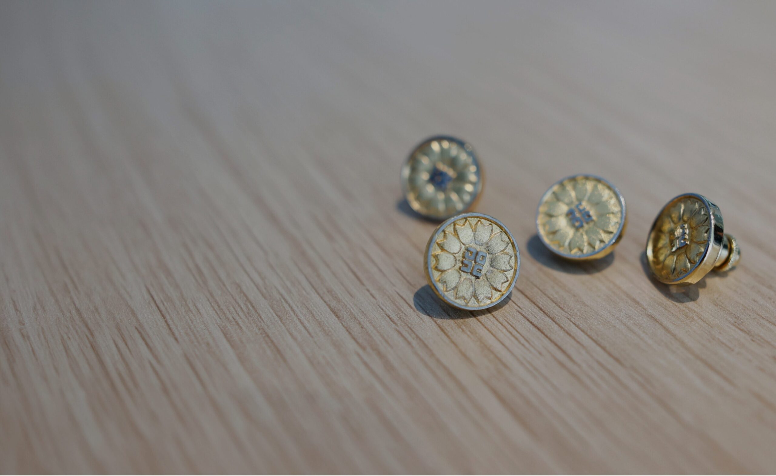 木製のテーブルの上に並ぶ士業バッジ。士業Webのファーストビューイメージ。